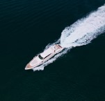A yacht cutting across dark water, seen from above