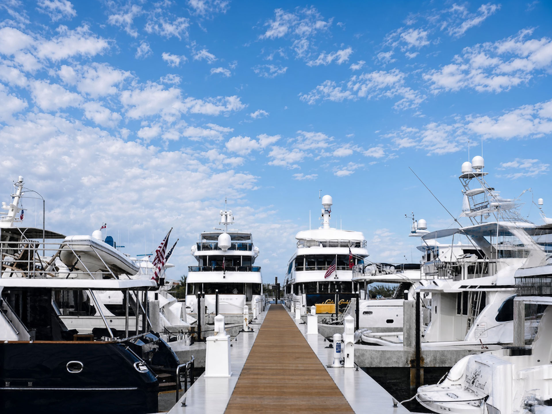 White yachts lined along a wooden dock under a blue sky