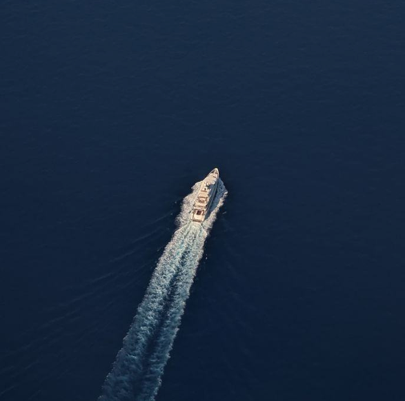A boat leaving a wake across deep blue water, seen from above