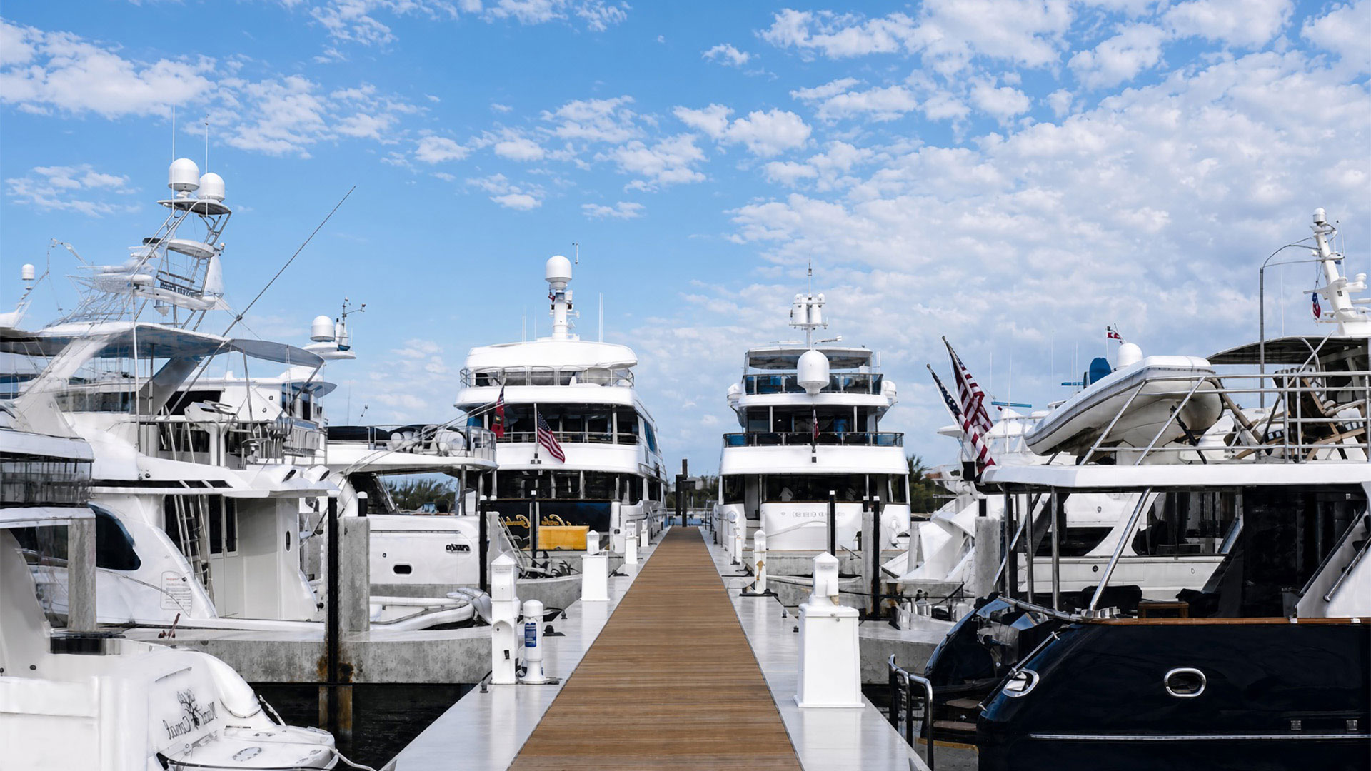 White yachts lined along a wooden dock under a blue sky